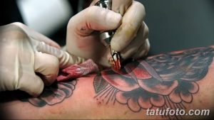 Фото процесса нанесения цветной татуировки. Мастер работает над рисунком на коже клиента, используя яркие краски.